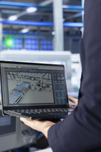 engineer in photovoltaics factory using tracking software on laptop